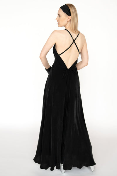 "Modele valkā melnu Cupro zīda trapece silueta maxi kleitu, demonstrējot tās piemērotību dažādiem ķermeņa tipiem un svētku pasākumiem. Model wearing the black Cupro silk trapeze silhouette maxi dress, showcasing its fit for various body types and special events."